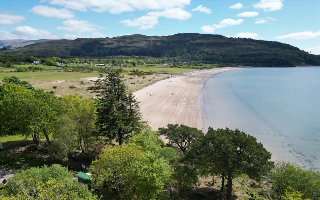 A sweeping view over Tralee Bay beach, calm water and wooded hills